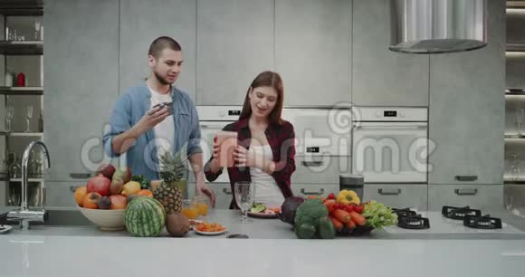 在一个现代化的厨房里一对漂亮的设计情侣在早上用搅拌机一起做一个健康的冰沙视频的预览图