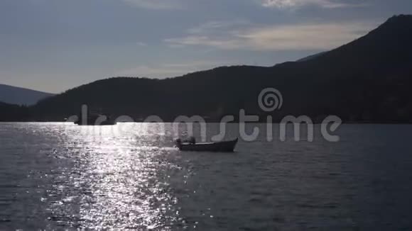 渔人剪影在背景夕阳下的河中钓鱼视频的预览图