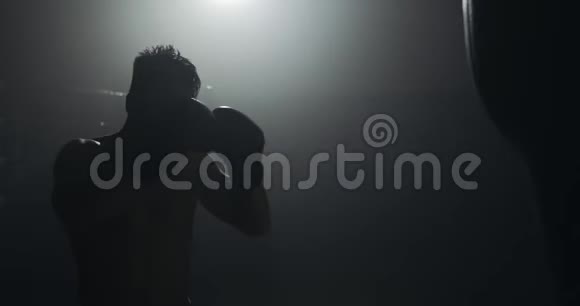 剪影拳击手在黑暗的健身房打拳关闭战斗机训练男拳击手在黑暗中锻炼跆拳道视频的预览图