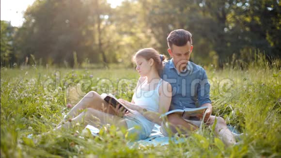 年轻漂亮的情侣夏天在户外看书微笑和亲吻视频的预览图