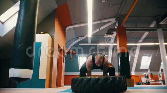 一个大个子健美运动员翻着地板上的轮胎移动着视频的预览图