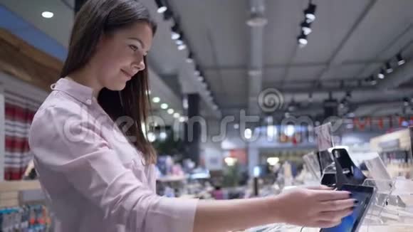 科技设备美丽的年轻女性顾客在电子商店里考虑新的现代上网本视频的预览图
