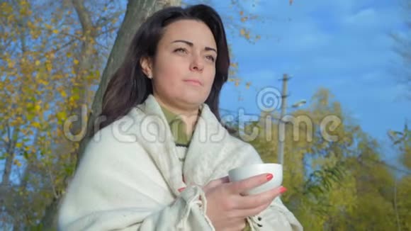 特写镜头美丽的女人在格子里手捧一杯茶在城市公园和看日出视频的预览图
