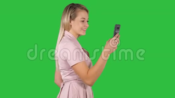 快乐的女人选择在线内容在智能手机上的绿色屏幕铬键视频的预览图