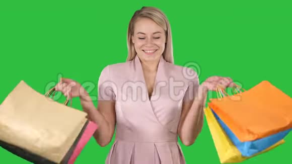 兴奋的漂亮年轻女士站着看相机在绿色屏幕上显示购物袋Chroma键视频的预览图