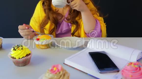 桌旁咖啡馆里的女孩喝茶用勺子吃蛋糕视频的预览图