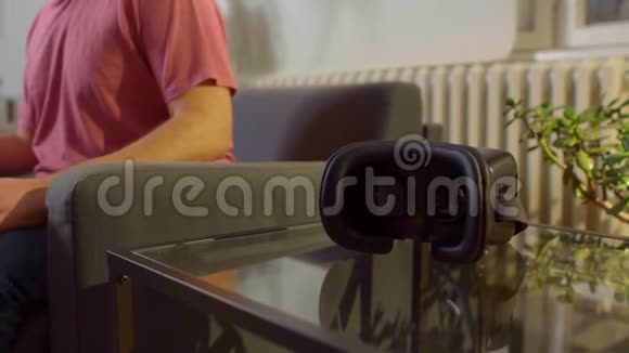 穿着粉色衬衫的男人在家里玩虚拟现实游戏视频的预览图