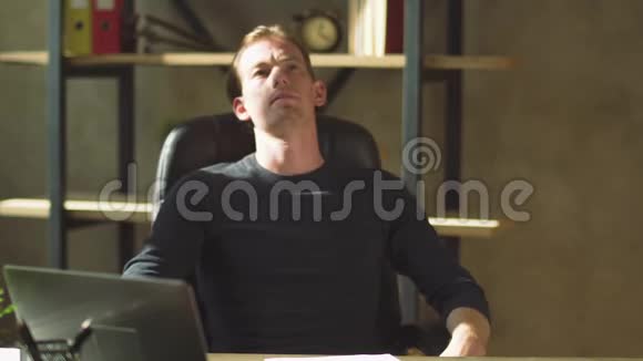 一个英俊而专注的商人坐在办公桌前在工作场所处理文件视频的预览图