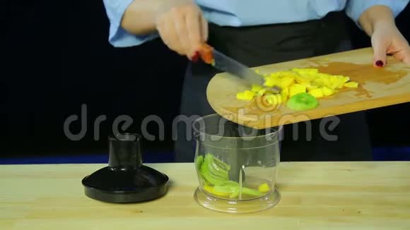 女人手把切好的猕猴桃和芒果放进搅拌碗里视频的预览图