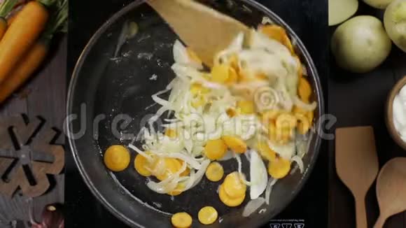 平躺视频厨师用木制厨房抹刀在热锅上搅动切碎的胡萝卜和洋葱以及炖菜的桌面视频的预览图