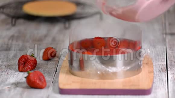 厨房里的女人做草莓慕斯蛋糕在糖果圈里浇草莓慕斯甜食视频的预览图