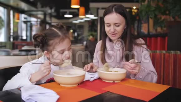 母亲和女儿在咖啡馆的一张桌子上吃热食从热的食物蒸汽上升视频的预览图