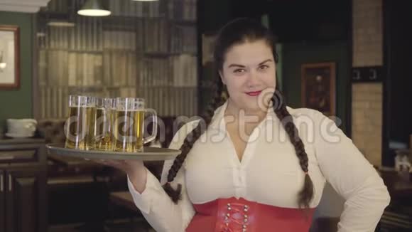 一个梳着辫子的女人穿着白色衬衫拿着托盘带着三个啤酒杯对着镜头微笑酒吧休闲视频的预览图