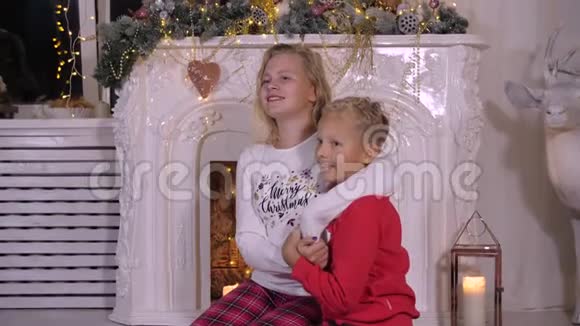 微笑的妹妹拥抱弟弟圣诞节壁炉背景视频的预览图