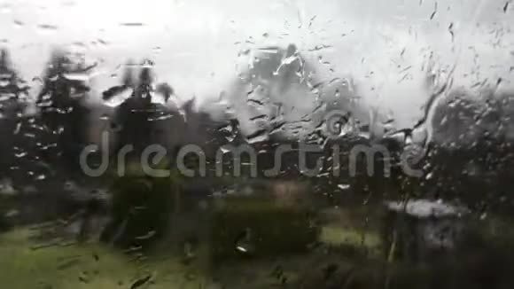 春天一列移动的火车的窗户上落下一滴雨水树灌木和房子经过视频的预览图