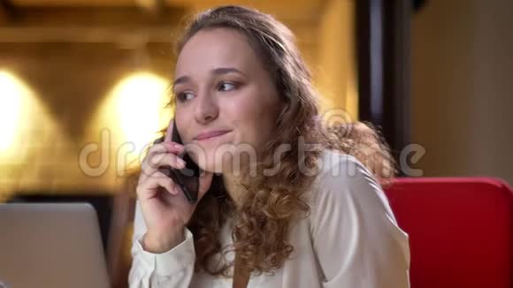 在办公室里一个情绪激动的卷发女人用手机愉快地交谈的特写镜头视频的预览图
