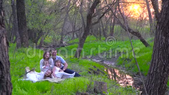 幸福的一家人在河边的公园里休息视频的预览图