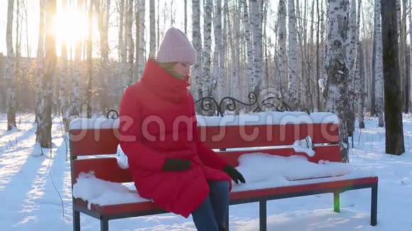 年轻女子坐在长凳上在画报城公园里用桦摸雪视频的预览图