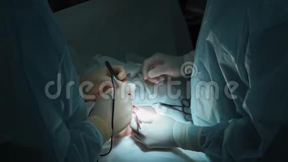 特写外科医生双手对患者做腹部手术光线低的场景慢动作视频的预览图