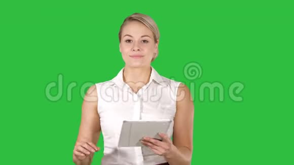 年轻微笑的商务女性带着平板电脑翻页看着绿色屏幕上的相机Chroma视频的预览图