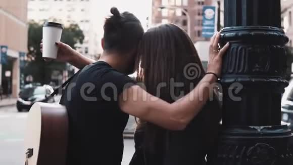 千禧浪漫夫妇拥抱在繁忙的街道上带吉他的欧洲男人和女孩牵手风吹进头发4K视频的预览图