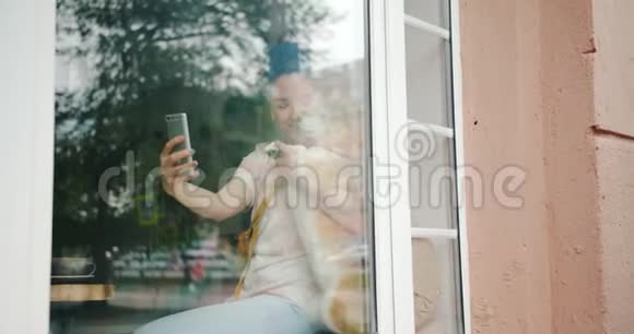 学生和宠物狗在窗台的咖啡馆里用智能手机自拍视频的预览图