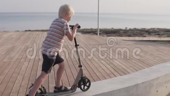 一个孩子在海边的公园里骑滑板车视频的预览图