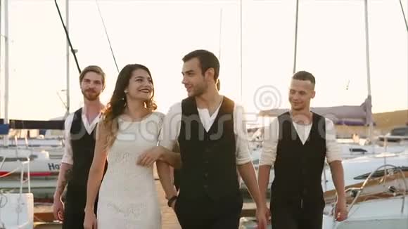 新婚夫妇和朋友在码头漫步那里有一艘船视频的预览图