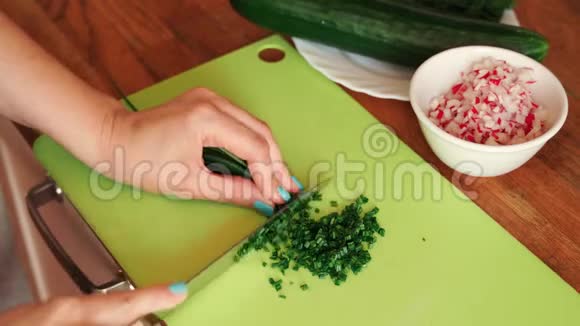 女人正在木桌上切厨房里的新鲜韭菜视频的预览图