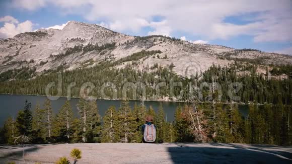 后景愉快兴奋的旅游女孩与背包享受惊人的山湖全景在约塞米蒂公园慢动作视频的预览图