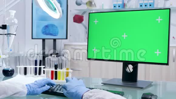 戴防护手套的化验师可在电脑上使用绿色屏幕视频的预览图