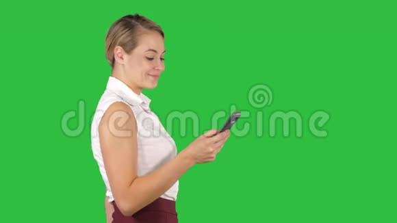 半长的肖像年轻女商人看她的手机在一个绿色屏幕Chroma键视频的预览图