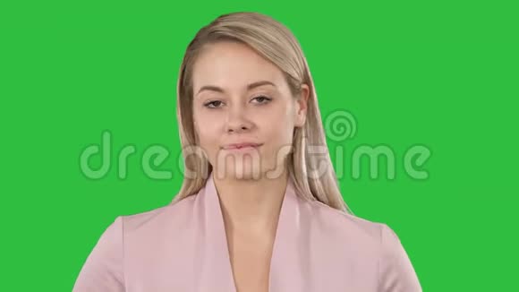 年轻美丽的女士穿着粉红色看着相机想着在绿色屏幕上微微微笑的东西Chroma键视频的预览图