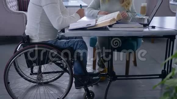 残疾人士的个人教育辅导女性眼镜为坐轮椅的残疾男子使用笔记本电脑上课视频的预览图
