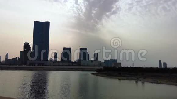日落时分城市摩天大楼在湖前消失AlReem阿布扎比视频的预览图