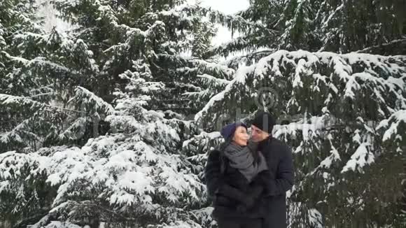 在白雪覆盖的树木附近微笑的夫妇视频的预览图