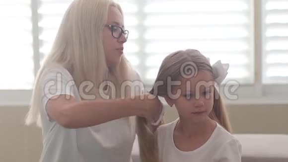 妈妈给一个蓝眼睛慢动作的小女孩梳头视频的预览图