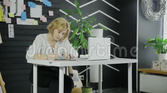 商务女性坐在桌旁时在贴纸上写下一些东西视频的预览图
