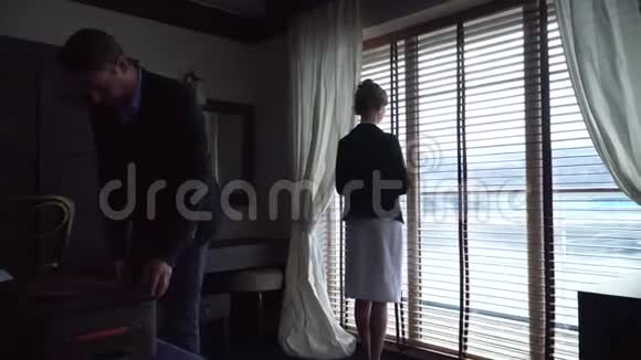 夫妇抵达现代酒店房间女孩来到窗口看着它男人加入她视频的预览图
