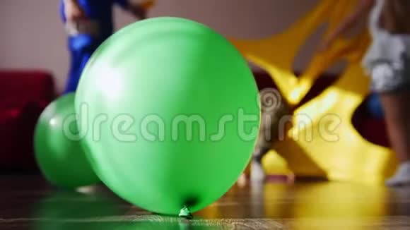 前景是一个绿色气球在孩子们后面玩玩得开心一个小男孩跑过去踢一个气球视频的预览图