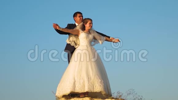新娘和新郎在蓝天上跳舞团队合作幸福的家庭观念浪漫的男人和女人在蓝色的上空盘旋视频的预览图