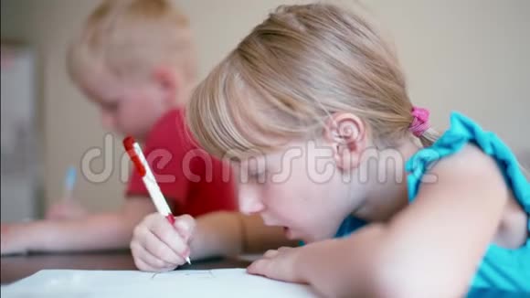 女孩和男孩在家里的办公桌上用彩色铅笔画纸视频的预览图