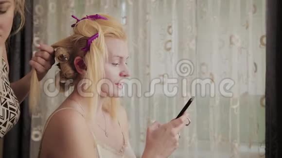专业的理发师女士正在做一个模特的发型照片她手里拿着一个电话视频的预览图