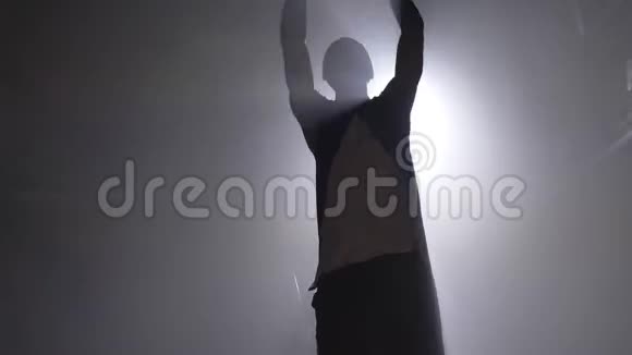 一名篮球运动员在室内篮圈练习和投掷球的剪影视频的预览图