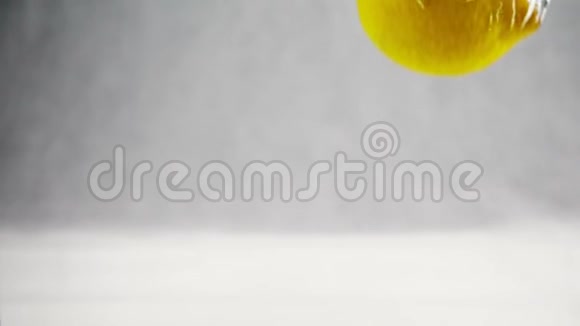明亮的黄色柠檬缓慢地掉进水里孤立白色背景上的水果视频的预览图
