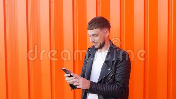 一个身穿黑色夹克衫手里拿着手机的年轻人抓住了一个移动网络一个快乐的家伙找到了一个移动网络邋遢视频的预览图