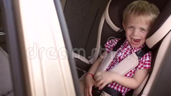 儿童汽车座椅上一个欢快笑男孩的肖像慢动作视频的预览图