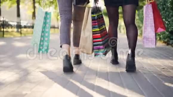 低角度拍摄的女人腿走在街上与五颜六色的纸袋后忙碌的一天在商店青年视频的预览图
