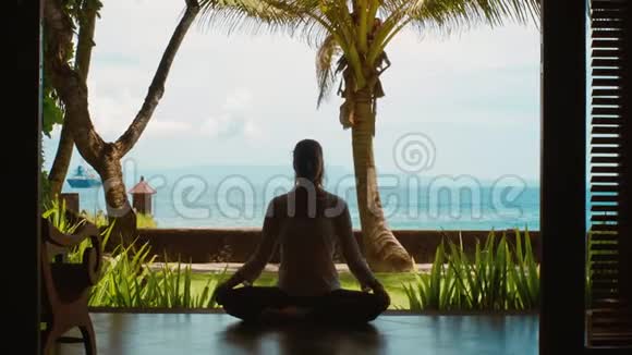 女人的剪影在莲花的位置练习瑜伽冥想在海滩上伸展双手美丽的景色自然的声音视频的预览图