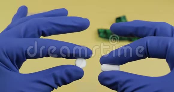 一个椭圆形和一个圆形的白色药丸手中穿着蓝色医用手套视频的预览图